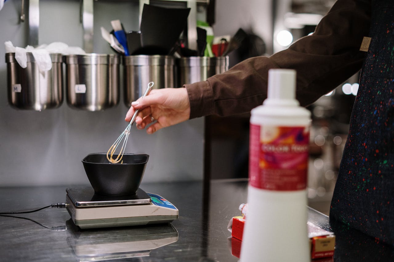 about-me-01 A stylist prepares hair dye with precision using professional tools in a salon setting.