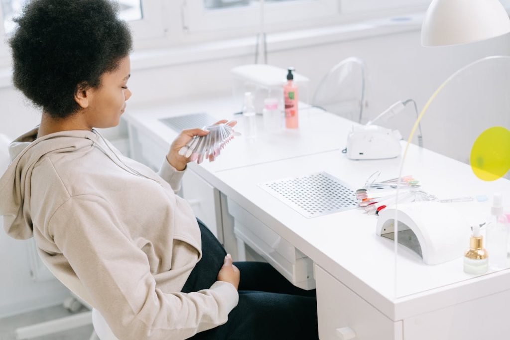 Pregnant woman selecting nail polish colors in a modern nail salon.